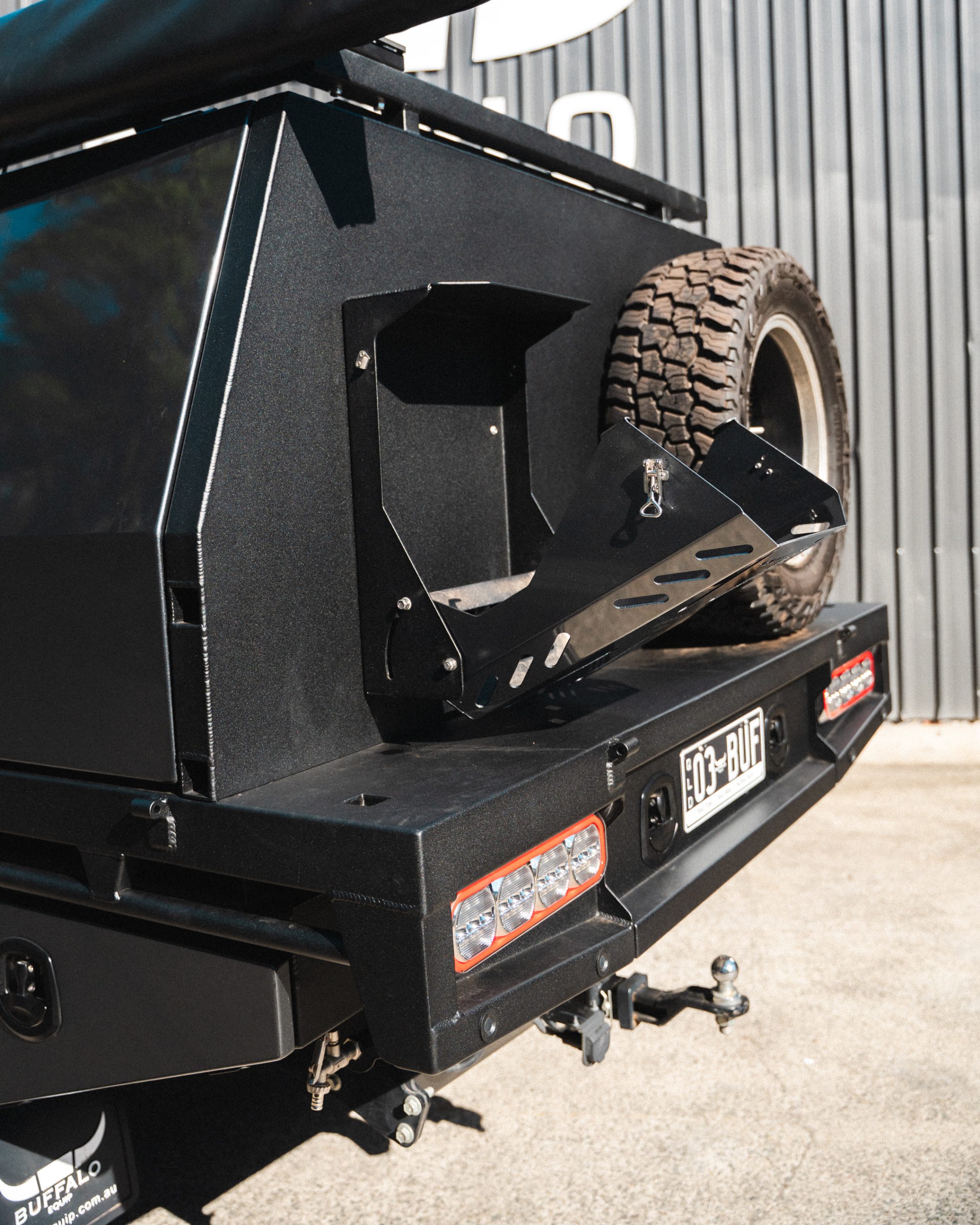 The back of a black powder coated canopy with Jerry can holder and wheel mount