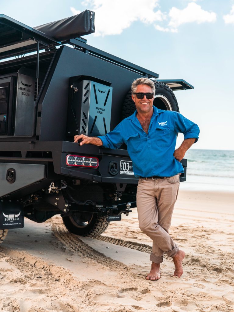 Owner of Buffalo Equip, Sam Anderssen leaning against canopy on beach